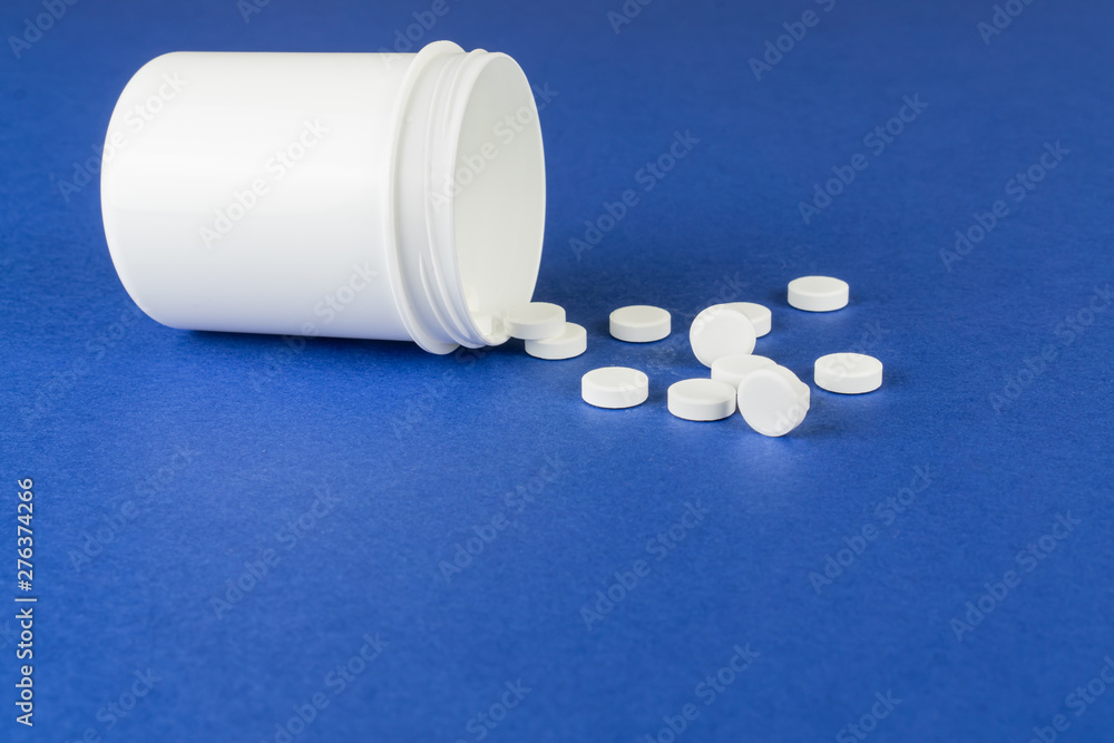 An opened drug can with tablets, blue background and copy space
