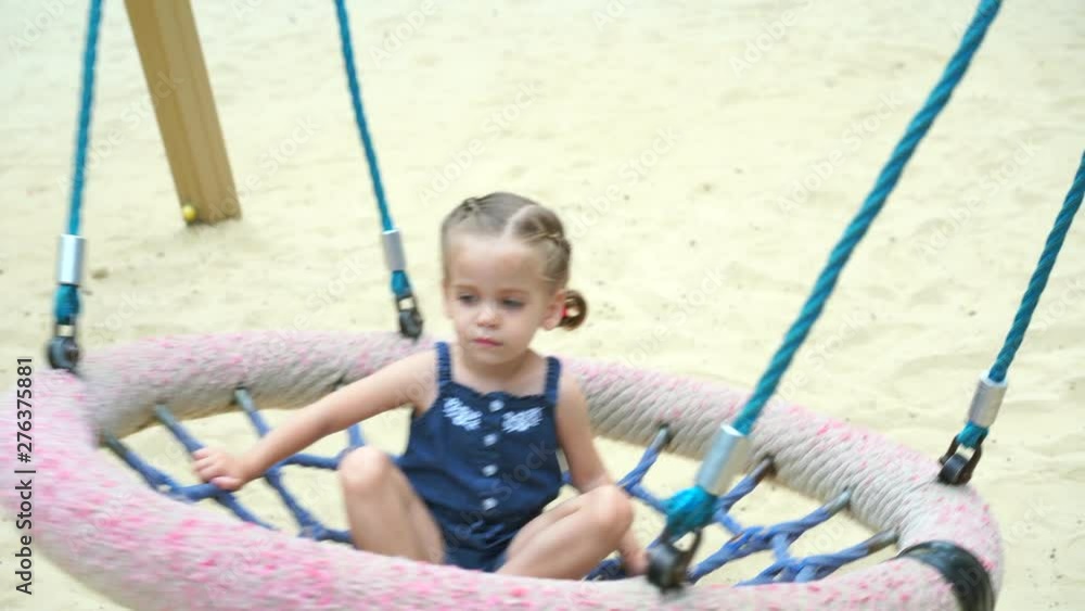 Child having fun on school yard playground. Active little girl playing on climbing net swing nest Child having fun on school yard playground. Active little girl playing on climbing net swing nest