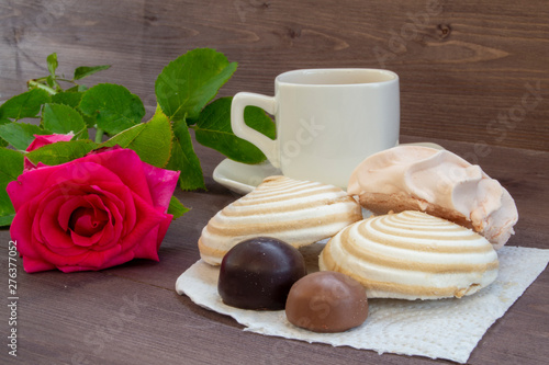 Delicate multicolored marshmallows on white openwork plate. Still life with marshmallows, a Cup of tea and a rose on vintage background.