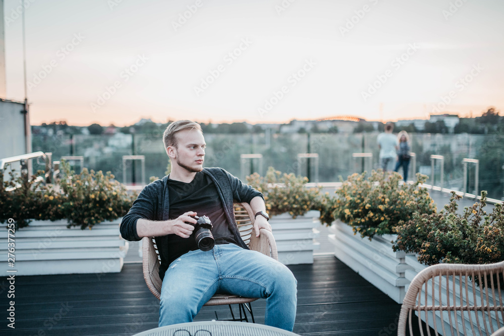 male photographer sits on a terrace overlooking the city and enjoys the cityscape male photographer sits on a terrace overlooking the city and enjoys the cityscape