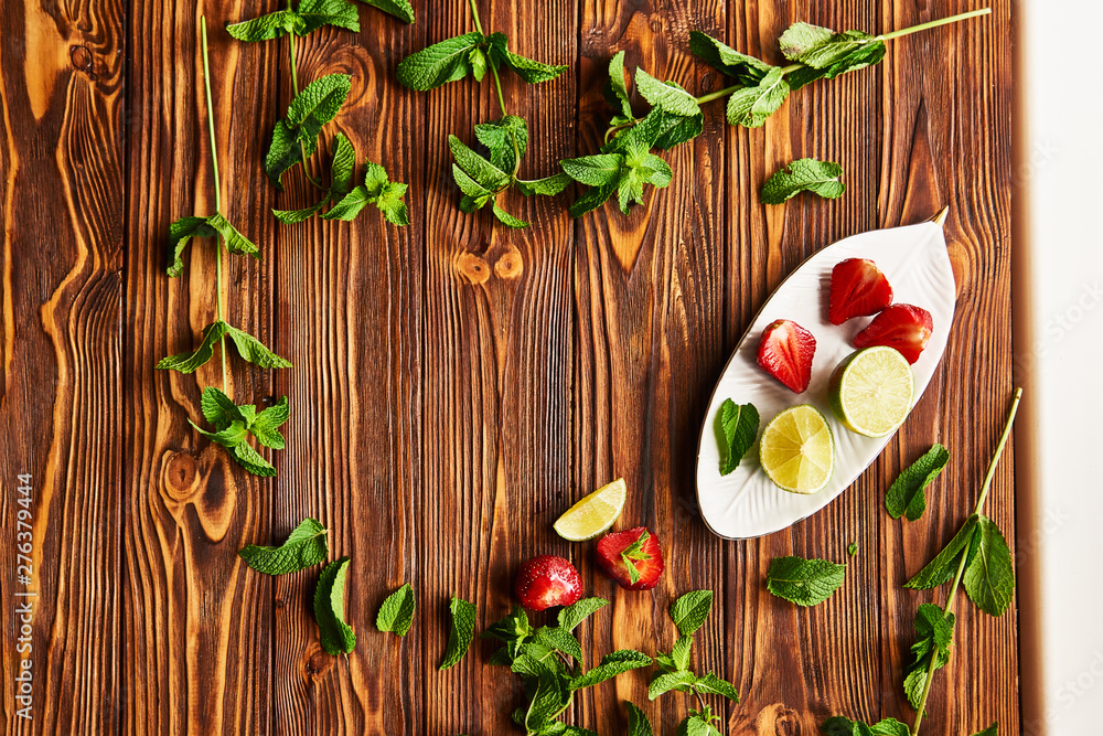 lime, strawberry, mint - ingredients for making lemonade on brown wooden table. empty space for text