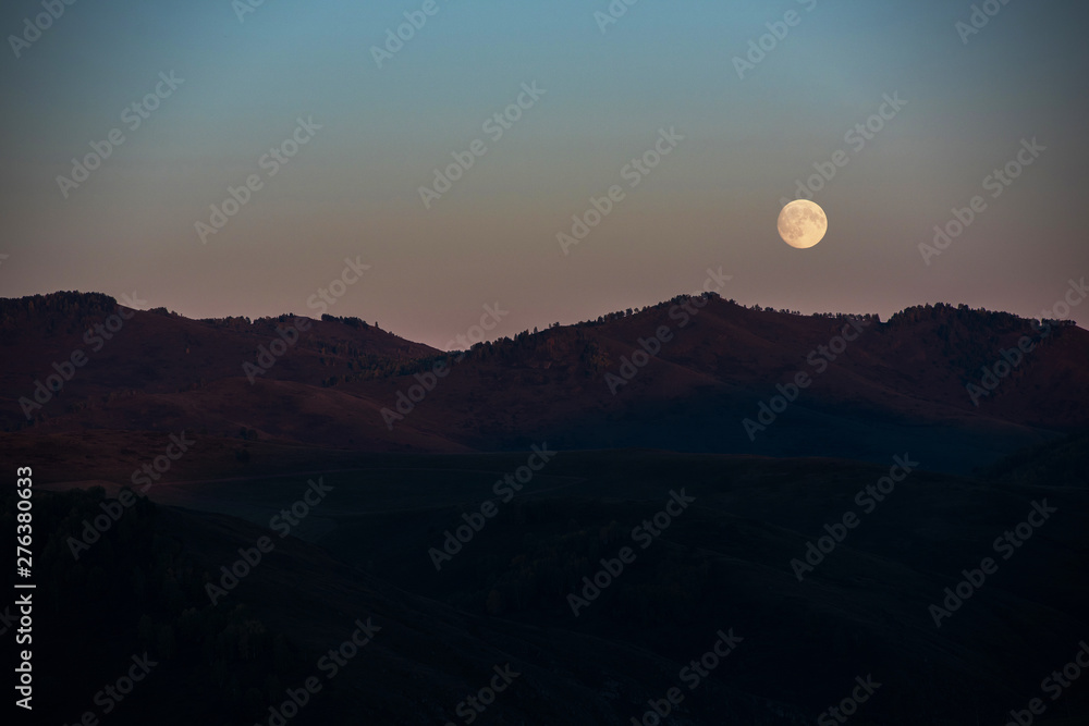 Full moon at sunset in Altai Mountains