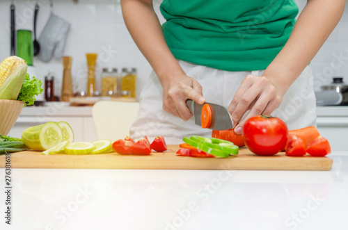 Diet. young pretty woman in green shirt cutting cooking and knife preparing fresh vegetables salad for good healthy in kitchen at home  healthy lifestyle  cooking  healthy food and dieting concept