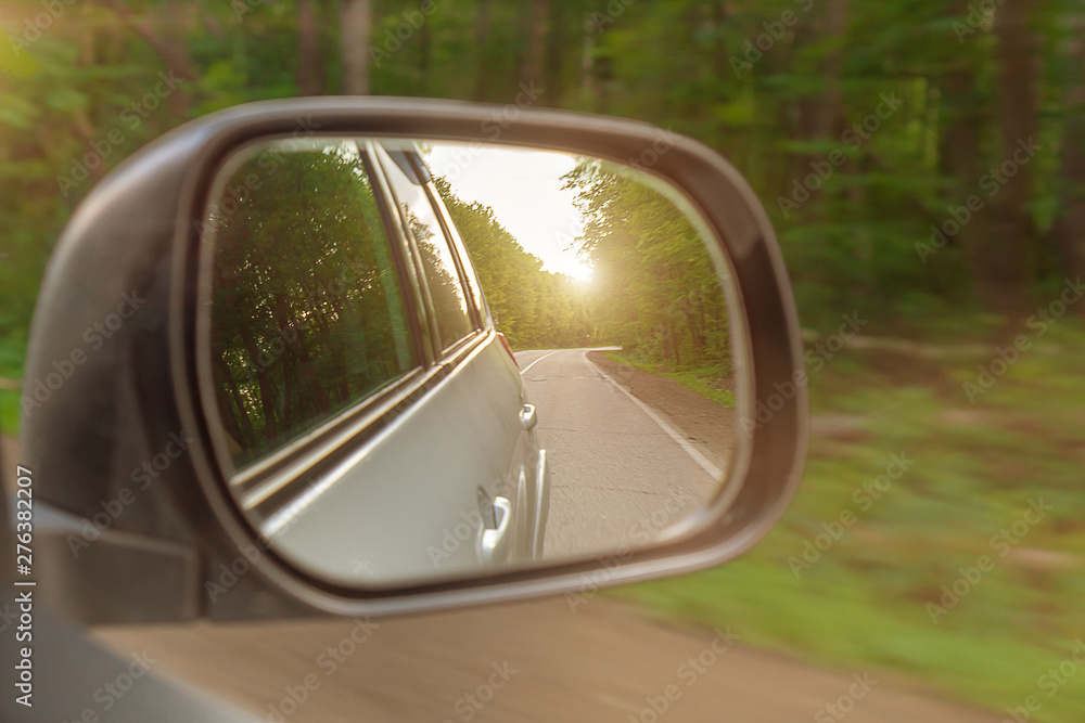 Landscape in the sideview mirror of a car , on road countryside. The sun is shining.