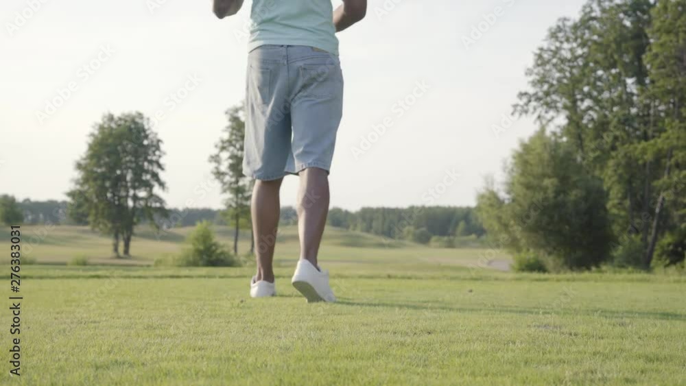 Unrecognized man playing golf on the golf field. Confident man warming up and hitting the ball using a golf club. The concept of recreation and sports outdoors. Unrecognized man playing golf on the golf field. Confident man warming up and hitting the ball using a golf club. The concept of recreation and sports outdoors.