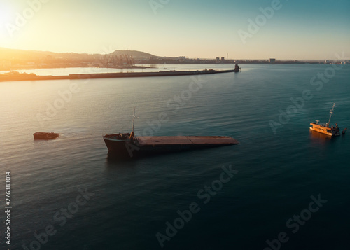 Aerial drone view of sunken cargo ship or tug boat near seaside. Shipwreck vessel with nose of ship above sea water