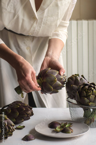 Woman wearing in white clean and cut fresh artichoke. Close up. photo