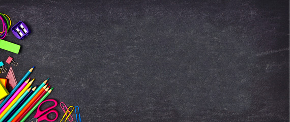 School supplies corner border banner. Top view on a chalkboard background with copy space. Back to school concept.