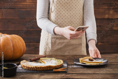 girl takes picture of pumpkin pie on mobile phone
