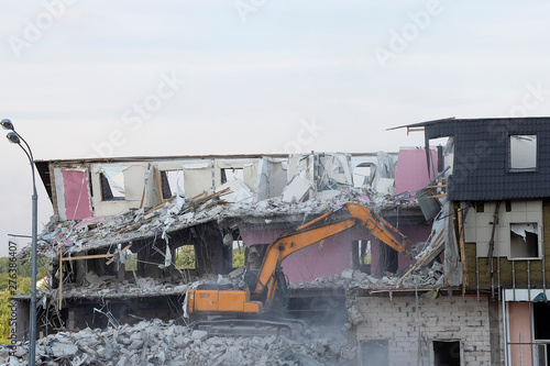An excavator demolishes a multi-storey building with a ladle. Technique destroys the building, is fittings, concrete and stones. Destroyed house, concrete, fittings. Similiar