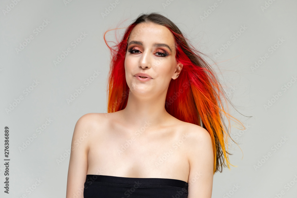 A close-up portrait photo of a fashionable hairstyle red-yellow in studio on a white background. The pretty brunette model with beautiful make-up has beautiful flowing colorful hair. A close-up portrait photo of a fashionable hairstyle red-yellow in studio on a white background. The pretty brunette model with beautiful make-up has beautiful flowing colorful hair.