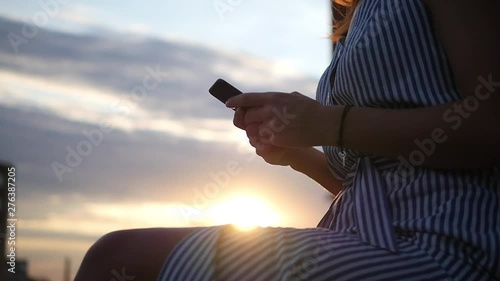 Mobile phone - Smartphone woman sms texting using app on smart phone at beach sunset. Mixed race Asian Caucasian girl using smart phone outdoors. Sunshine and flare. Cell phone close up