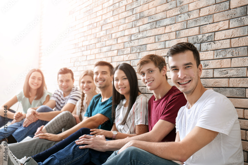People sitting together near brick wall. Unity concept People sitting together near brick wall. Unity concept
