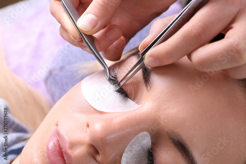 Young woman undergoing eyelash extensions procedure, closeup