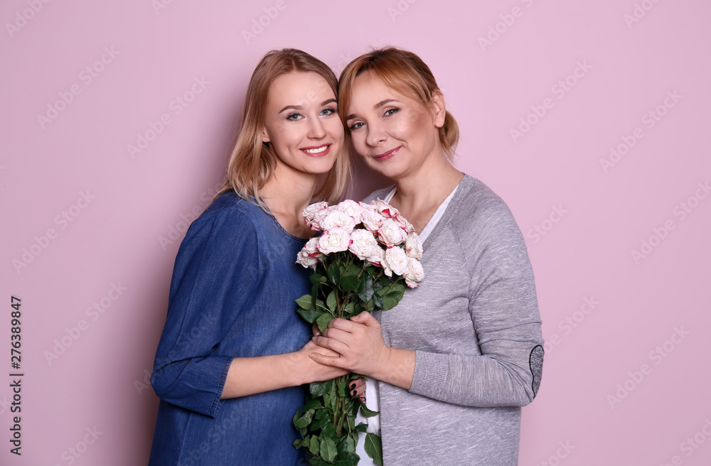 Young woman and her mother with bouquet of flowers on color background Young woman and her mother with bouquet of flowers on color background