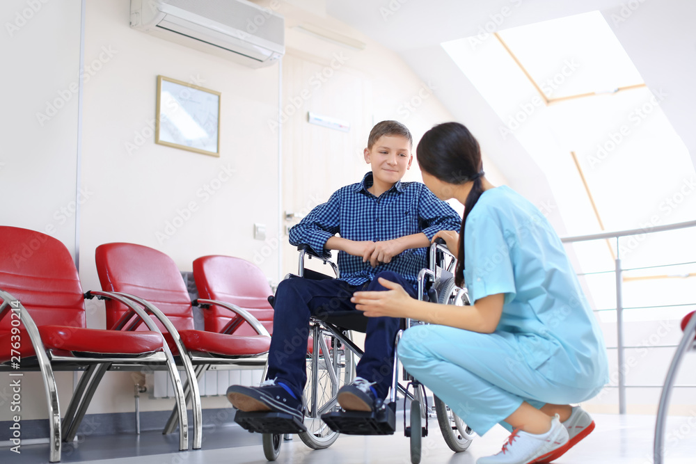 Φωτογραφία Young female doctor taking care of little boy in wheelchair indoors