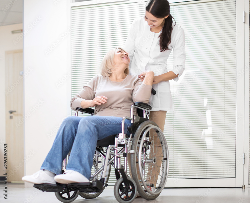 Φωτογραφία Young female doctor taking care of mature woman in wheelchair indoors