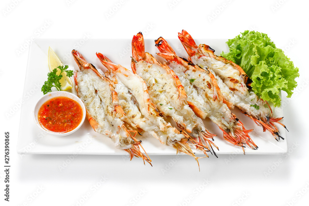 Grilled 5 black tiger shrimps with boiled potatoes, slice of lime, tomato fresh vegetables and chili seafood sauce on white square plate isolated on white background with shadow high angle Top view Grilled 5 black tiger shrimps with boiled potatoes, slice of lime, tomato fresh vegetables and chili seafood sauce on white square plate isolated on white background with shadow high angle Top view