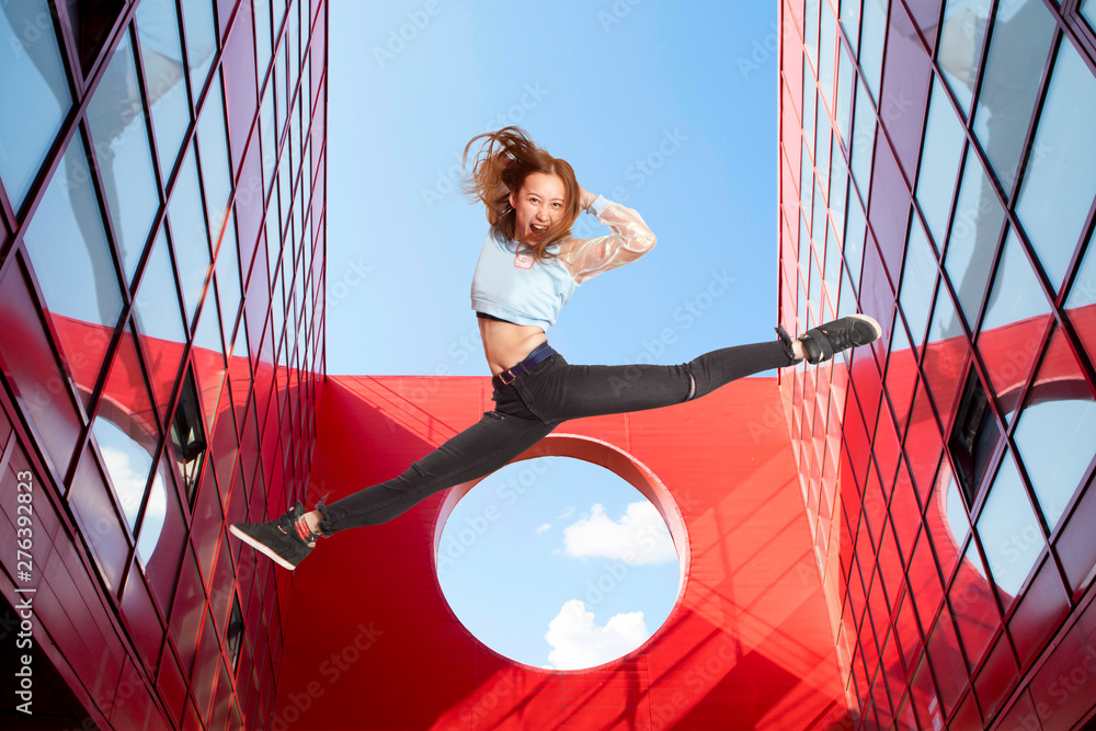 Fit woman jumping on urban red background - Image - obrazy, fototapety, plakaty 