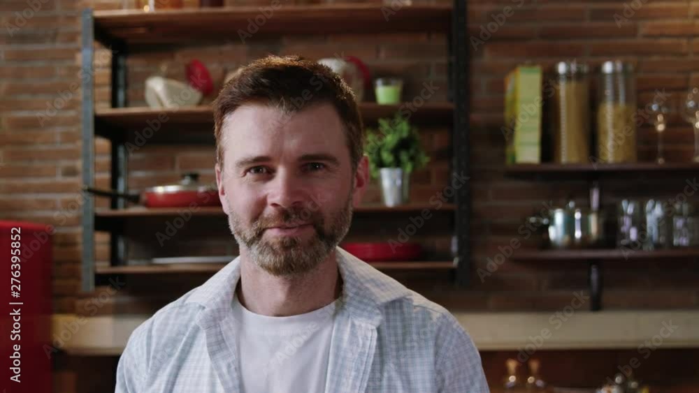 Close-up of attractive cheerful fun man watching close with amazed expression waving hands and smiling broadly on camera in the kitchen at home. Close-up of attractive cheerful fun man watching close with amazed expression waving hands and smiling broadly on camera in the kitchen at home.