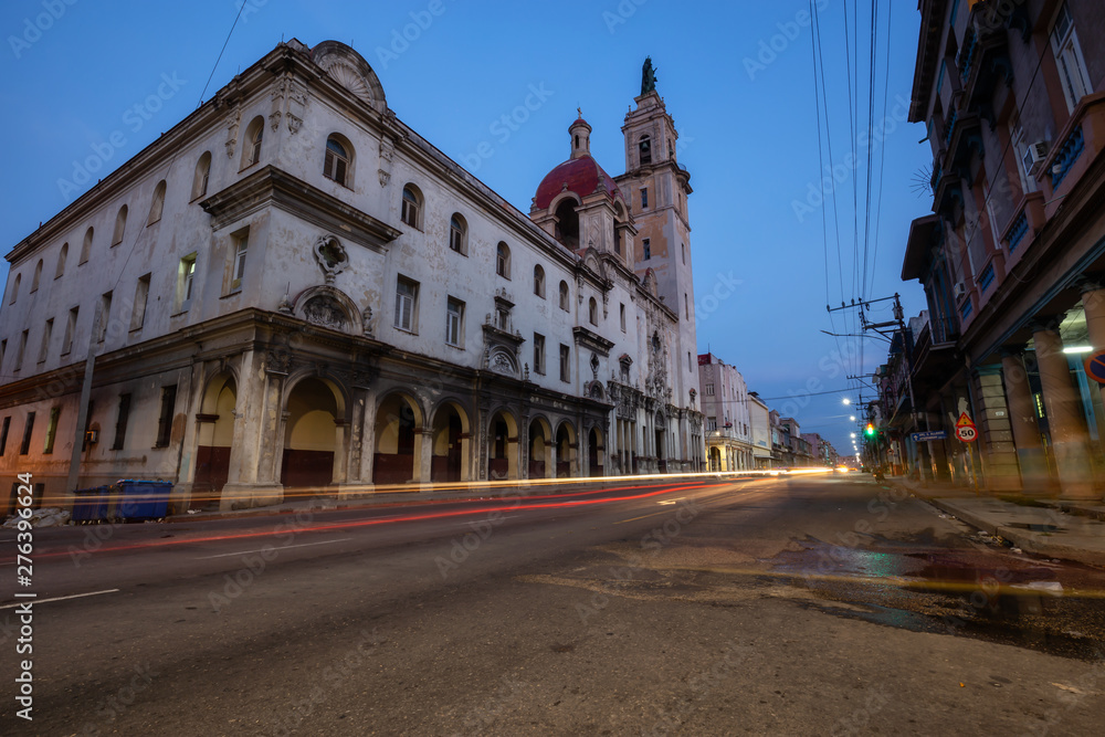 Street view of the busy road with traffic  with Catholic Church building in the background in the Old Havana City, Capital of Cuba, during night time after sunset.