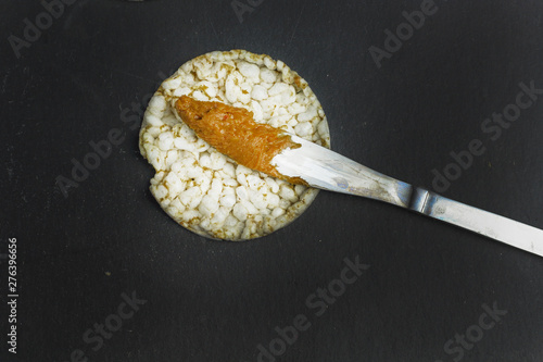 crunchy natural peanut butter sandwich  on rice cake bread on black slate background with knife peanut butter with knife with free copy space. Proper nutrition diet vegetarian breakfast