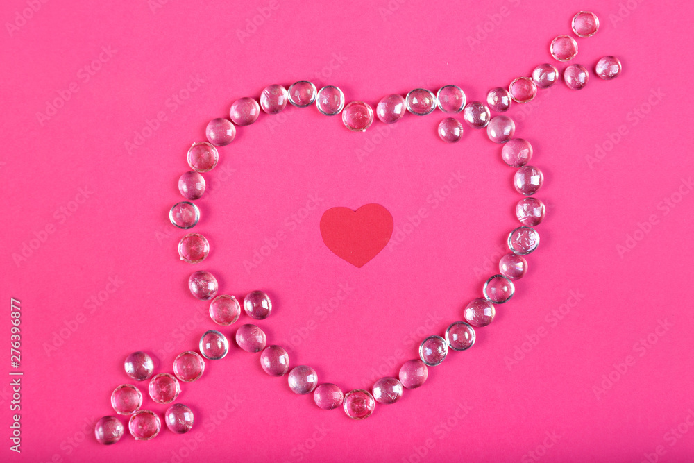 Heart lined with beads with an arrow on a pink background with a heart in the middle.