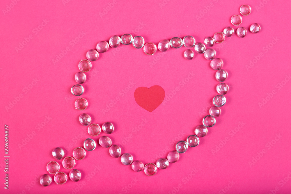 Heart lined with beads with an arrow on a pink background with a heart in the middle. Heart lined with beads with an arrow on a pink background with a heart in the middle.
