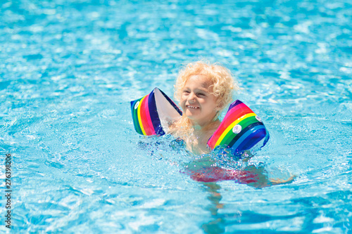 Child in swimming pool. Kid with float armbands.
