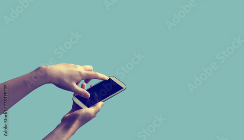 Person holding a white smartphone on a solid colored background