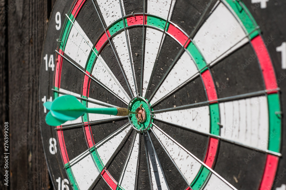 Darts board on the wall with wooden boards. Darts driven into the center Darts board on the wall with wooden boards. Darts driven into the center