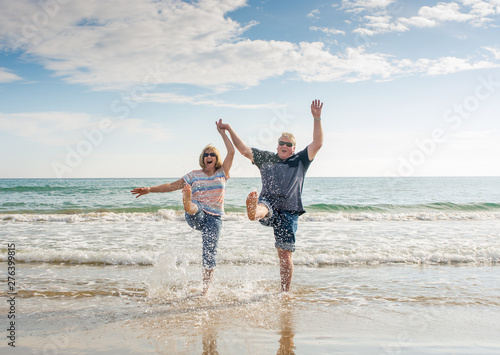 Senior couple in love walking on the beach having fun in a sunny day