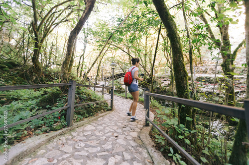 female tourist with backpack walking in park, Rear view © producer