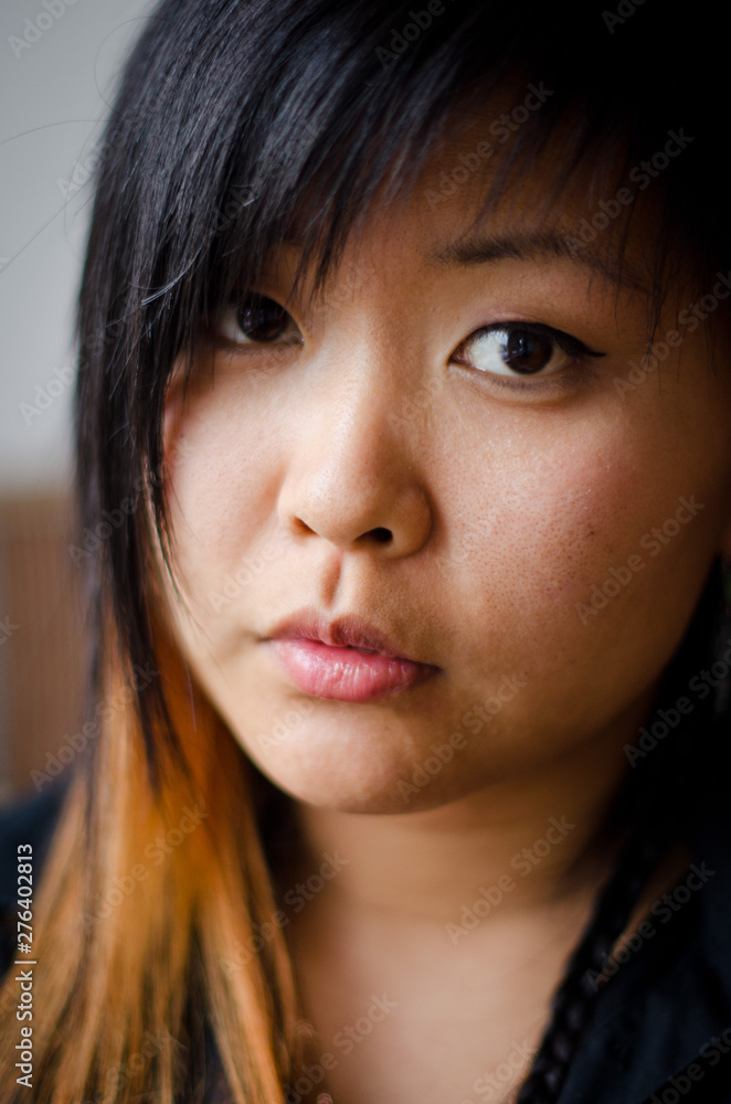 Close up young Asian woman with a serious face and beautiful eyes, short hair and a red strand Close up young Asian woman with a serious face and beautiful eyes, short hair and a red strand