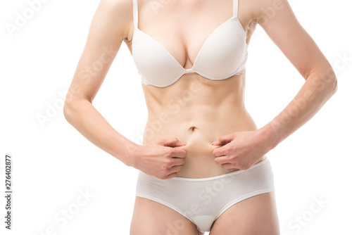 cropped view of woman in underwear holding skin on belly isolated on white
