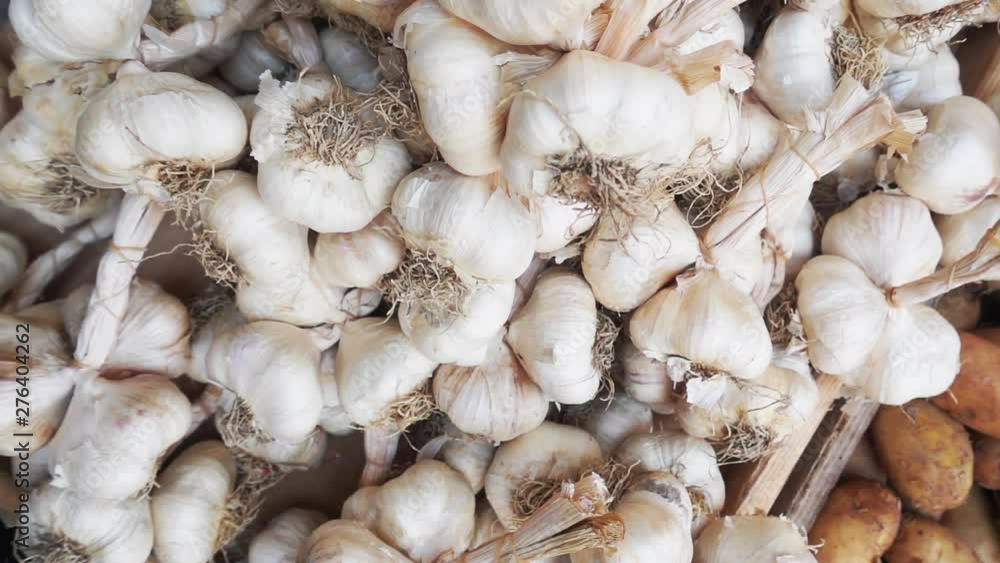 Top view slow motion tracking shot over a pile of many white garlic bulbs on display at a farmers street market. Top view slow motion tracking shot over a pile of many white garlic bulbs on display at a farmers street market.