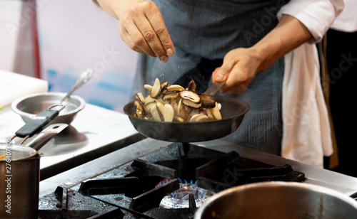 chef frying mushrooms in the kitchen of the restaurant