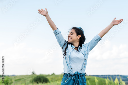 cheerful young woman with closed eyes and outstretched hands
