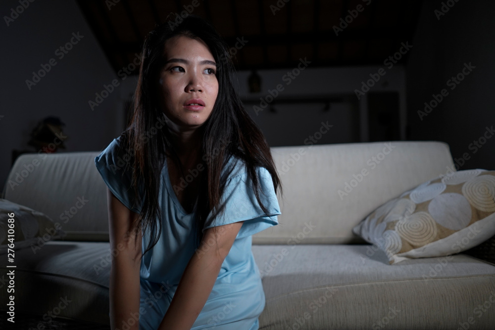 dramatic lifestyle portrait of young desperate sad and depressed Asian Chinese woman sitting at home sofa couch suffering depression problem and anxiety crisis feeling lonely and helpless dramatic lifestyle portrait of young desperate sad and depressed Asian Chinese woman sitting at home sofa couch suffering depression problem and anxiety crisis feeling lonely and helpless