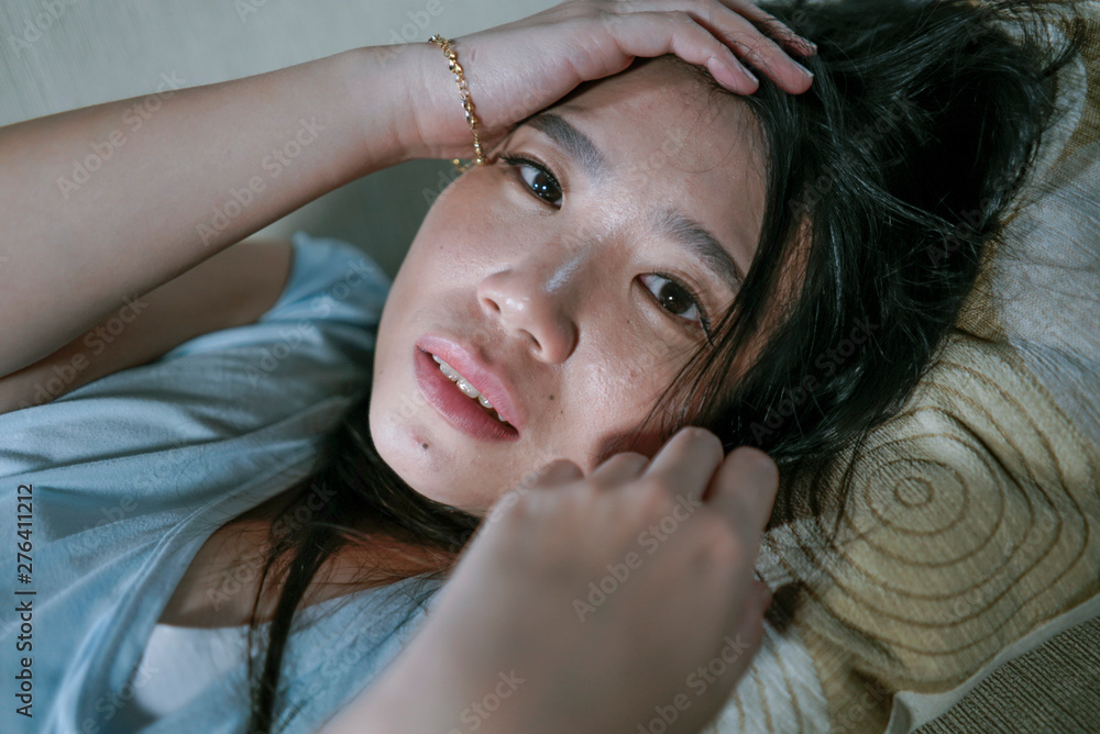 Fototapeta premium young desperate sad and depressed Asian Korean woman sitting at home sofa couch suffering depression problem and anxiety crisis feeling lonely