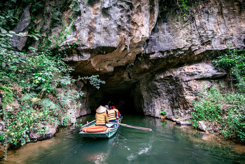 Boat cave tour in Trang An Scenic Landscape formed by karst towers and plants along the river (UNESCO World Heritage Site). It's Halong Bay on land of Vietnam. Ninh Binh province, Vietnam. Boat cave tour in Trang An Scenic Landscape formed by karst towers and plants along the river (UNESCO World Heritage Site). It's Halong Bay on land of Vietnam. Ninh Binh province, Vietnam.