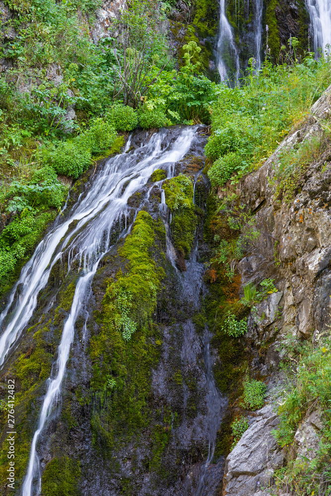 mountain wooded waterfall among the rocks in summer
