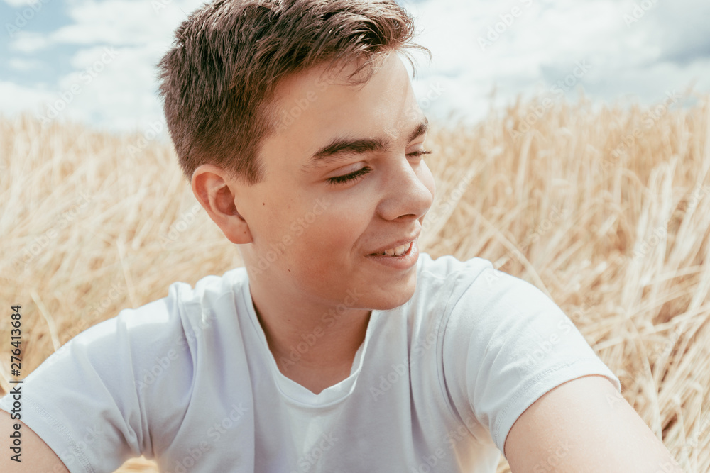 Portrait of handsome teenage boy outdoors, in front of wheat field, at summer day. Portrait of handsome teenage boy outdoors, in front of wheat field, at summer day.