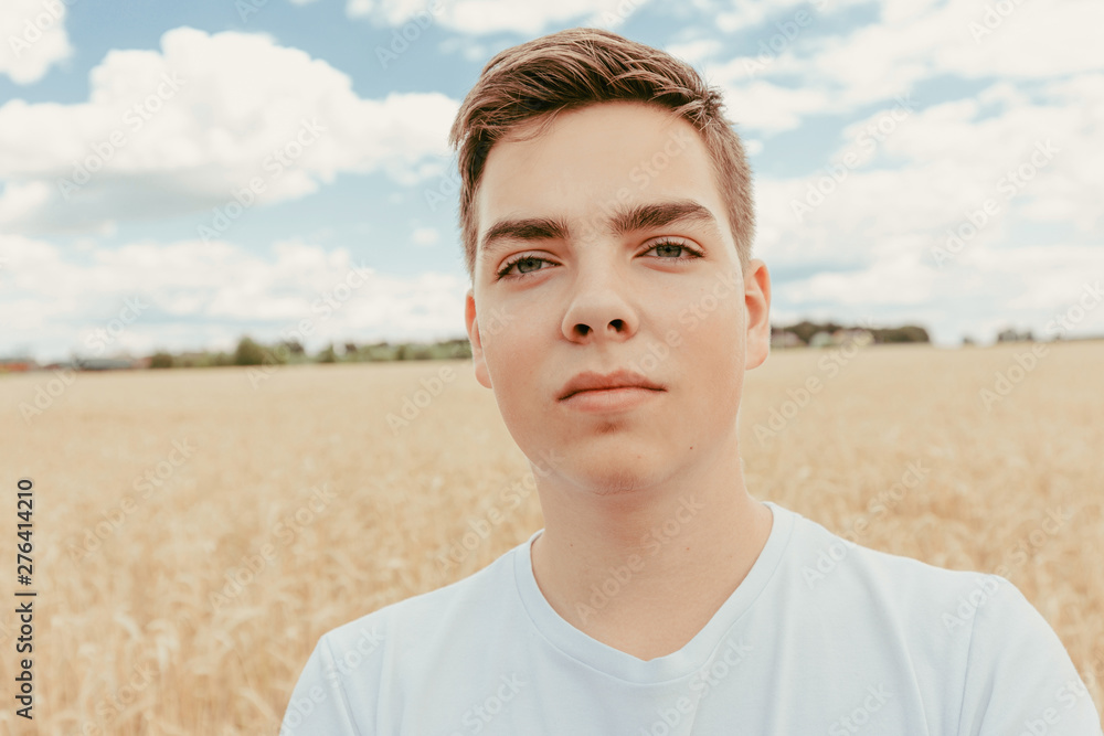 Portrait of handsome teenage boy outdoors, in front of wheat field, at summer day. Portrait of handsome teenage boy outdoors, in front of wheat field, at summer day.