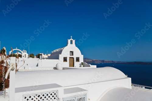 Old white ortodox church in sunny day with blue sky in Oia on Santorini island low view