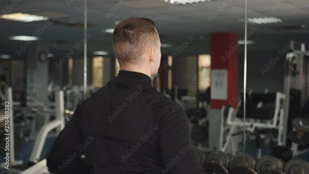 A man trains his biceps with dumbbells and looks at his body in the mirror. A man trains his biceps with dumbbells and looks at his body in the mirror.