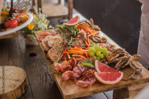 A buffet of assorted cured meats, sausages, ham, fruits, vegetables, olives, pickled, bread and sauce for an event or party.