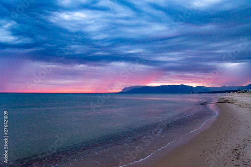 Scenic gray-blue clouds during sunrise over coastline with sandy beach and clear sea water in Alcamo Marina, small town in Sicily, Italy, summer vacation destination