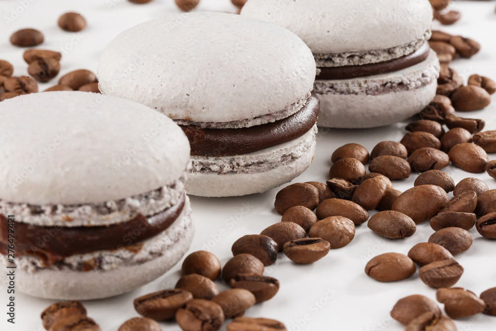 French macaroons isolated with coffee beans. Selective focus. macaroon in gray tone. Beautiful macaroons on marble background. Stylish arrangement sweet. Flat lay, top view.