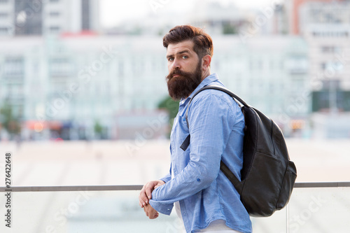 Backpack for travelling and city life. Hipster wearing backpack in casual style on urban outdoor. Bearded man travelling with backpack on summer vacation. Taking backpack in backpacking trip photo